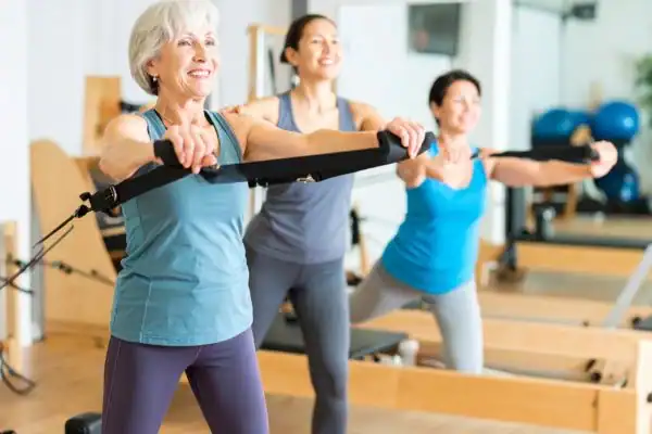 Toning Arms After 60: Empowering Womens Fitness Through Effective Weight Training 2 older woman doing weight training Buckingham and resistance in the gym to tone upper arms