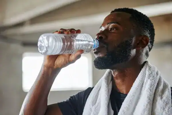 Hydration: The Secret Ingredient for a Toned Stomach and Enhanced Fitness 1 Image of man drinking water to improve hydration Buckingham after work out.